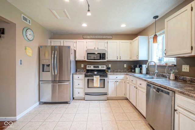 kitchen with stainless steel appliances, a sink, decorative light fixtures, dark countertops, and recessed lighting