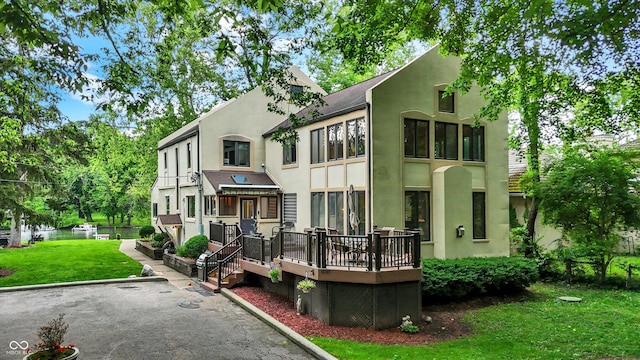 1530 E 75th St, Indianapolis, IN 46240 - rear view of house featuring stucco siding, a lawn, and a deck with water view