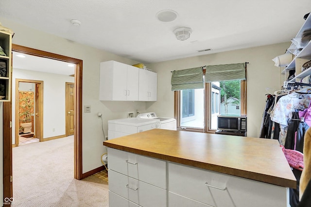 1530 E 75th St, Indianapolis, IN 46240 - kitchen with washer and clothes dryer, white cabinetry, light carpet, baseboards, and stainless steel microwave