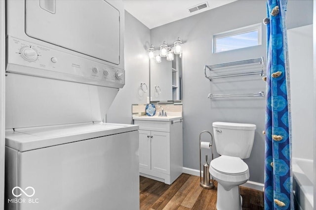 744 Gilbert Ave, Indianapolis, IN 46227 - full bathroom featuring stacked washer / dryer, wood finished floors, toilet, vanity, and a shower with shower curtain