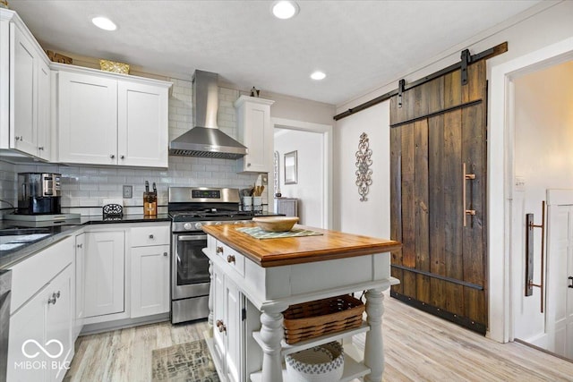 744 Gilbert Ave, Indianapolis, IN 46227 - kitchen with wall chimney range hood, stainless steel range with gas stovetop, wooden counters, light wood-style floors, and backsplash