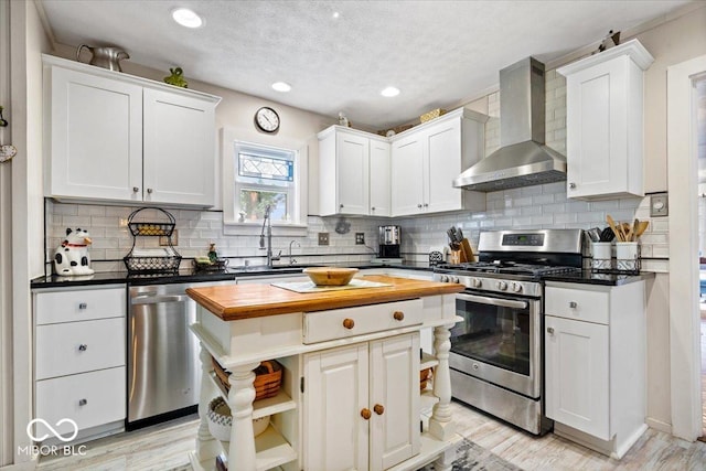 744 Gilbert Ave, Indianapolis, IN 46227 - kitchen featuring appliances with stainless steel finishes, wall chimney exhaust hood, butcher block counters, a kitchen island, and a sink