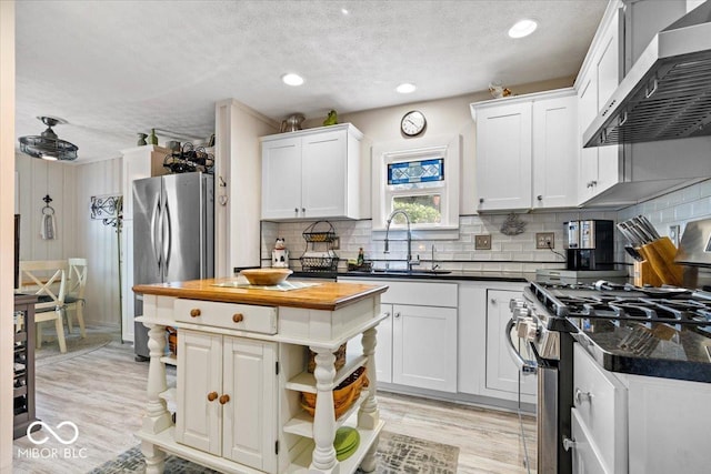 744 Gilbert Ave, Indianapolis, IN 46227 - kitchen featuring wall chimney exhaust hood, a sink, appliances with stainless steel finishes, a textured ceiling, and white cabinets