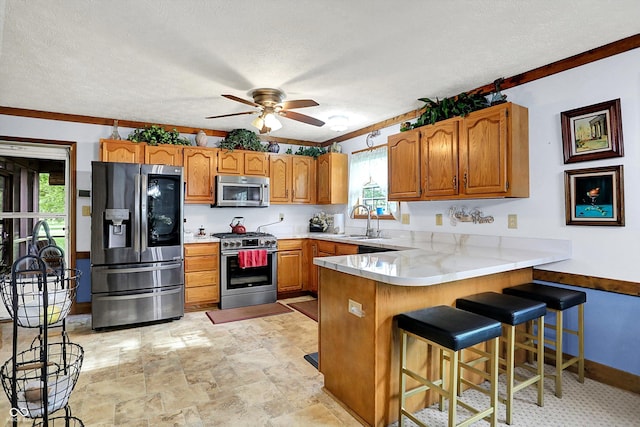 7655 N Kitchen Rd, Mooresville, IN 46158 - kitchen with stainless steel appliances, a peninsula, a sink, brown cabinets, and a ceiling fan