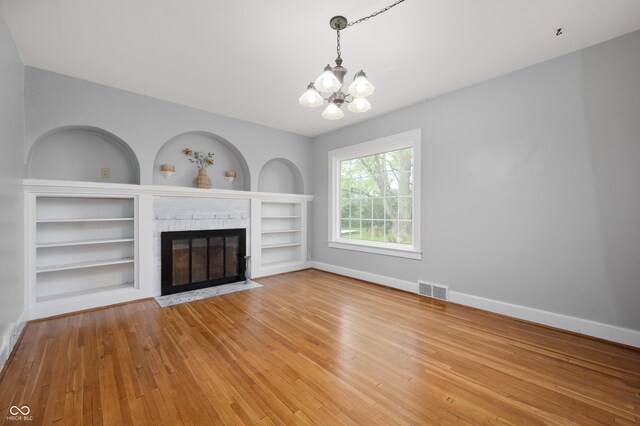 6851 W County Road 550 S, Daleville, IN 47334 - unfurnished living room with a chandelier, a fireplace, hardwood / wood-style floors, baseboards, and built in features