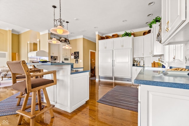 3107 Waterfront Cir, Anderson, IN 46012 - kitchen with crown molding, light wood finished floors, white cabinetry, a sink, and a center island