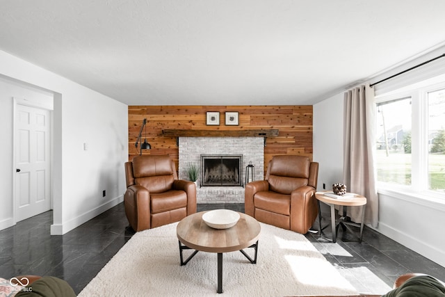 living area with baseboards, wooden walls, a brick fireplace, and an accent wall