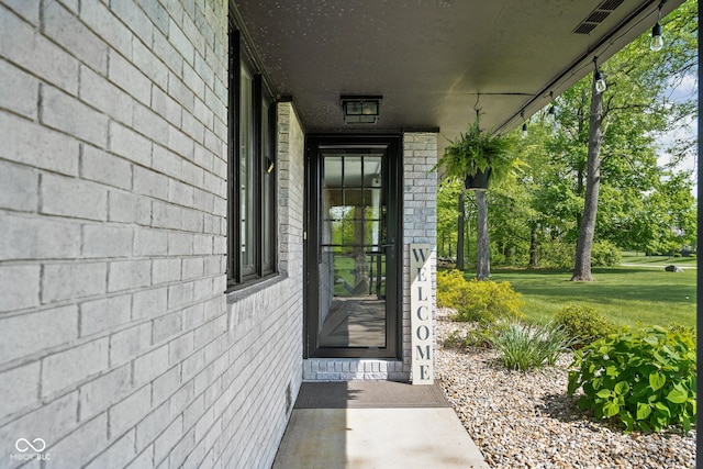 view of exterior entry featuring a lawn