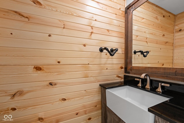 bathroom featuring wooden walls and a sink