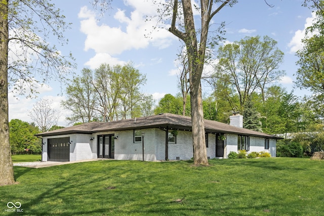 view of front of home featuring a garage, a chimney, a front yard, driveway, and brick siding