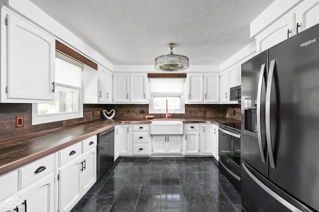 kitchen with black appliances, decorative backsplash, white cabinetry, wood counters, and a textured ceiling