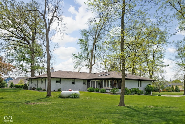 back of property featuring a yard, a chimney, brick siding, and cooling unit
