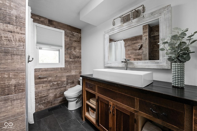 bathroom with toilet, vanity, and wooden walls
