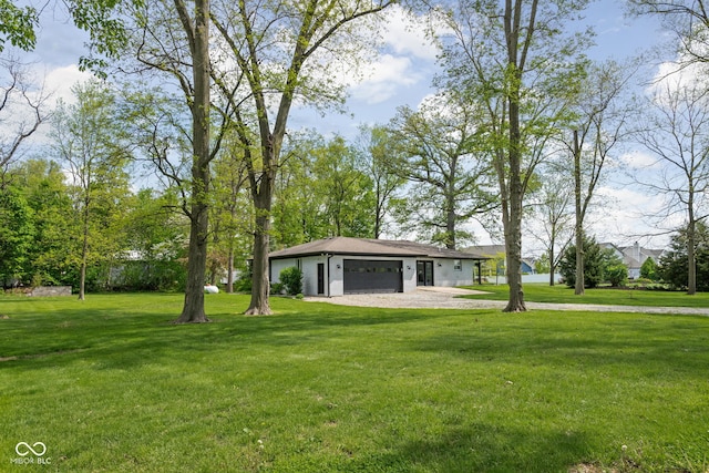 view of front of home with an attached garage, a front lawn, and gravel driveway