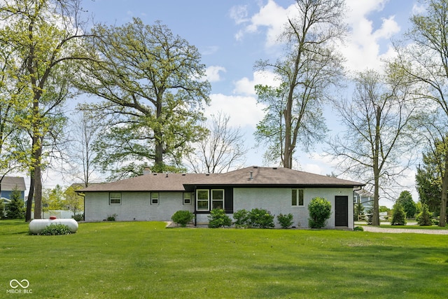 rear view of house with a yard, a chimney, and brick siding