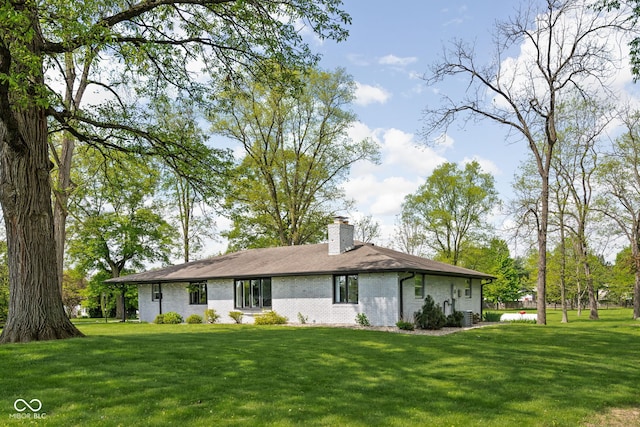 back of house with a lawn, a chimney, and brick siding