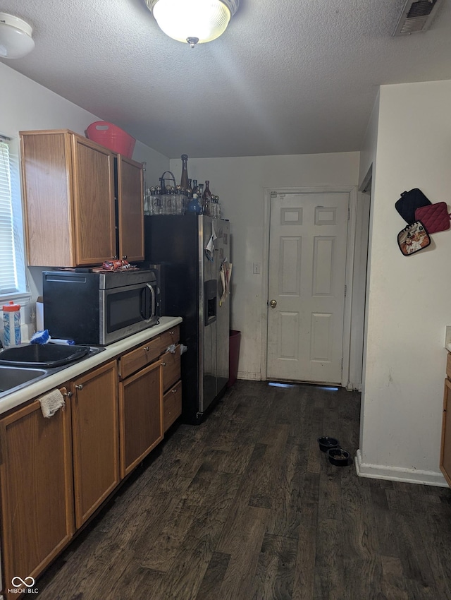 10425 Candy Apple Ln, Indianapolis, IN 46235 - kitchen featuring stainless steel appliances, dark wood-type flooring, light countertops, brown cabinetry, and a textured ceiling