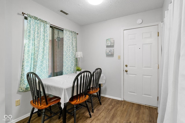 dining space featuring wood finished floors, baseboards, and a textured ceiling