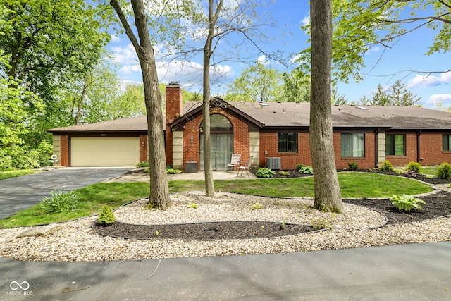 single story home with brick siding, driveway, a chimney, a garage, and central AC unit