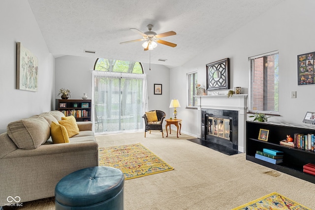 carpeted living room with a ceiling fan, a fireplace with flush hearth, lofted ceiling, a textured ceiling, and plenty of natural light