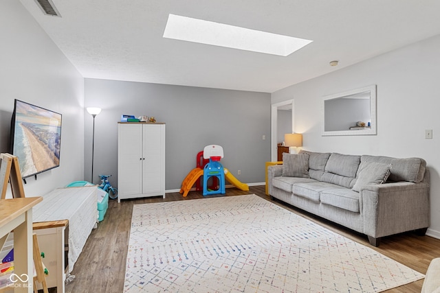 living area with a skylight, wood finished floors, and baseboards