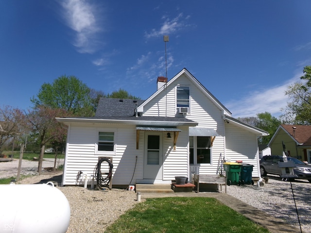rear view of property with a chimney and roof with shingles
