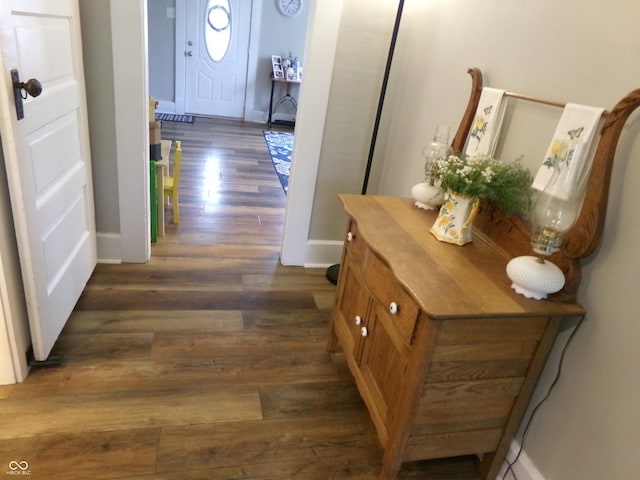 corridor featuring dark wood-style flooring and baseboards