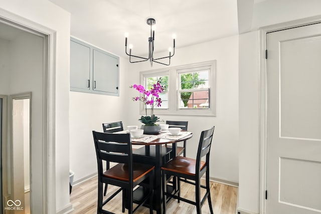 dining space with a chandelier, light wood-style flooring, and baseboards