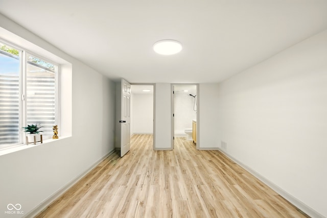 unfurnished bedroom with light wood finished floors, baseboards, and ensuite bath