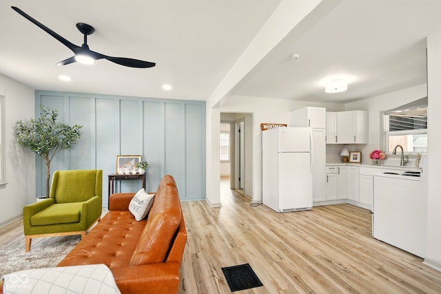 kitchen featuring freestanding refrigerator, range with electric stovetop, ceiling fan, light wood-style flooring, and a decorative wall