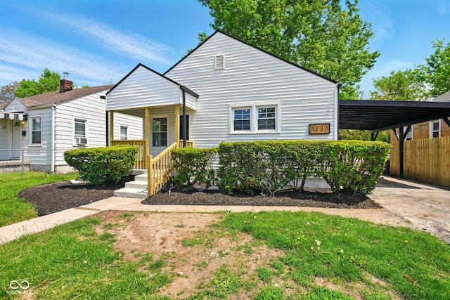 view of front of property with fence, a carport, cooling unit, concrete driveway, and a chimney