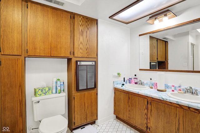 full bathroom featuring toilet, double vanity, and tile patterned floors