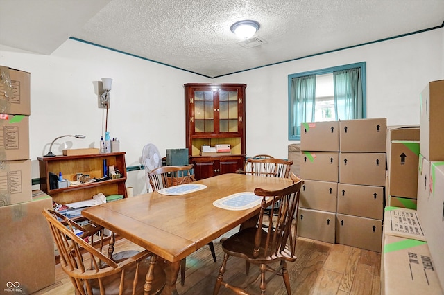 dining space with wood finished floors and a textured ceiling