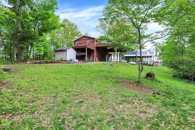 view of green lawn with an outbuilding, a wooden deck, and a shed