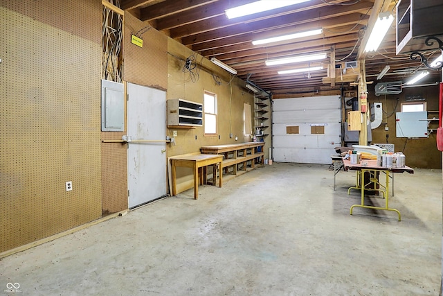 garage featuring a workshop area, electric panel, and heating unit