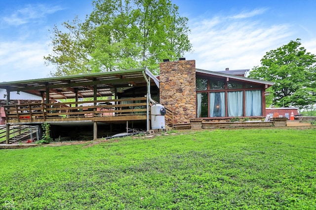 rear view of house with a yard, a chimney, and a wooden deck
