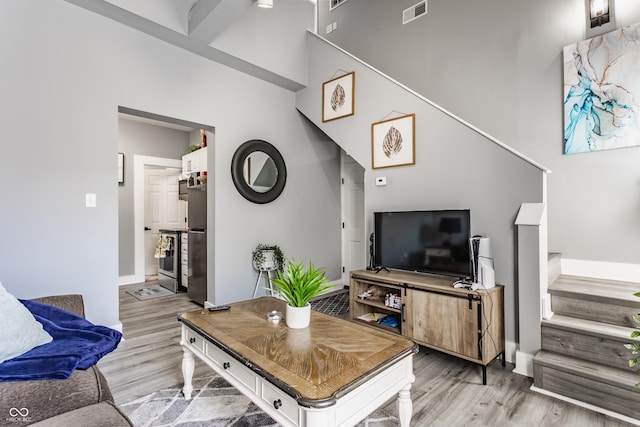 living area with light wood-style flooring, baseboards, and stairway