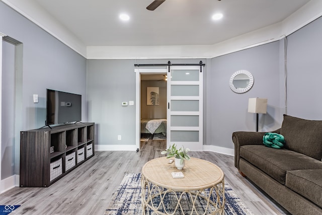 living area featuring a barn door, wood finished floors, ceiling fan, baseboards, and recessed lighting