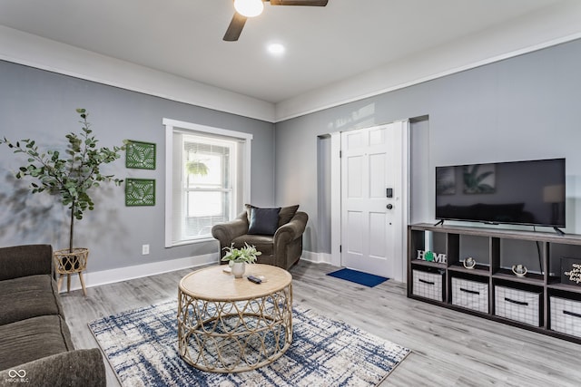 living area with a ceiling fan, wood finished floors, and baseboards