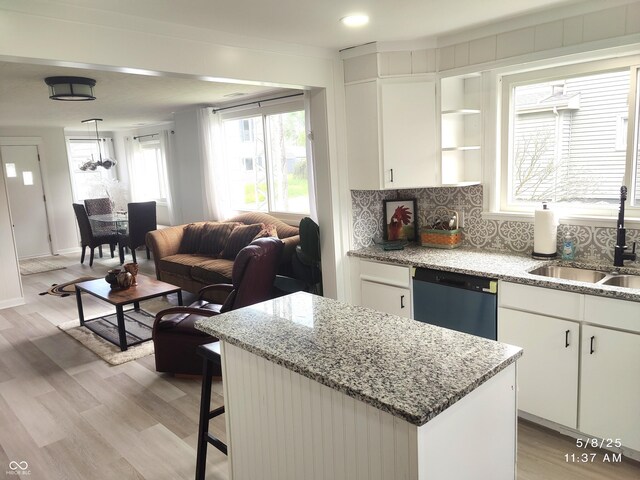 kitchen with a sink, dishwasher, tasteful backsplash, a kitchen island, and white cabinets