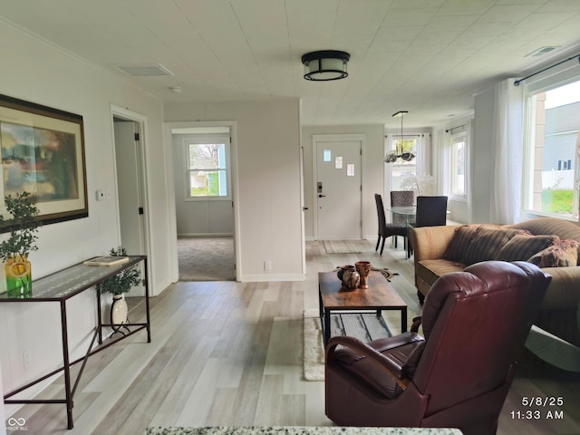 living area featuring plenty of natural light, light wood finished floors, and a chandelier