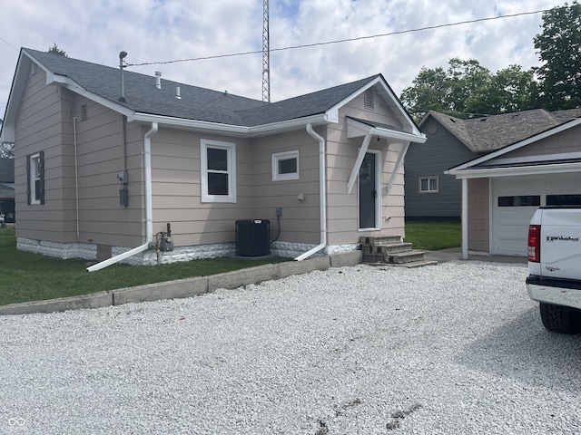 view of front of house featuring central air condition unit, entry steps, a garage, roof with shingles, and gravel driveway