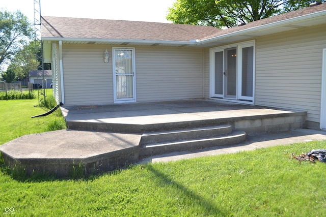 rear view of property featuring a lawn, a patio area, and a shingled roof