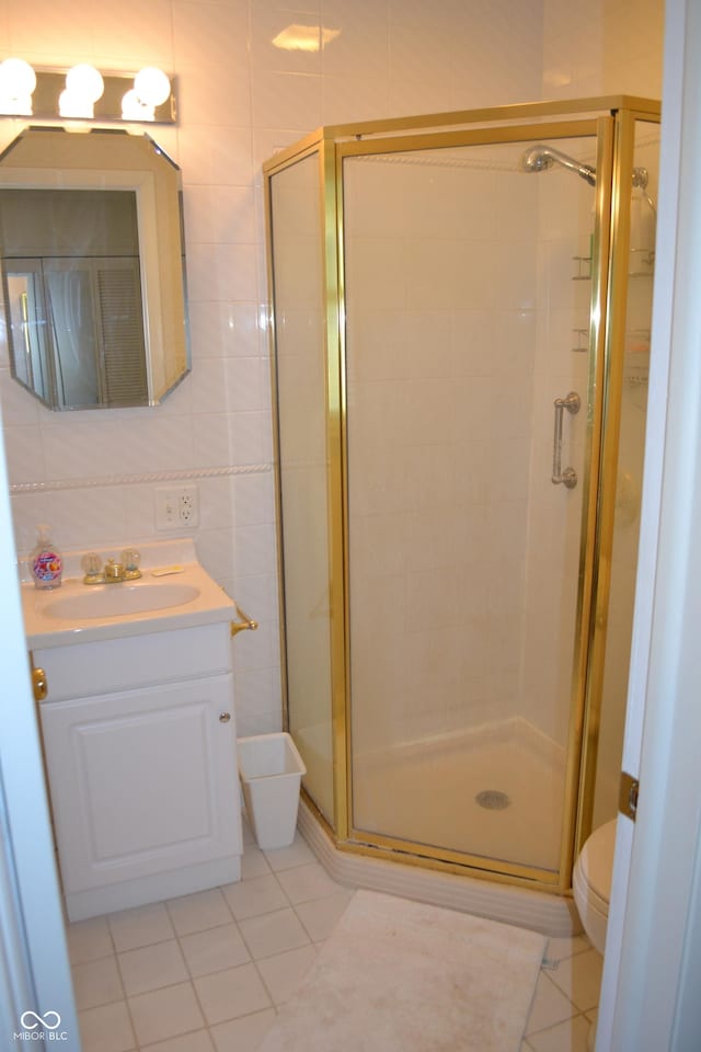 full bathroom with tile patterned floors, toilet, tile walls, a stall shower, and vanity