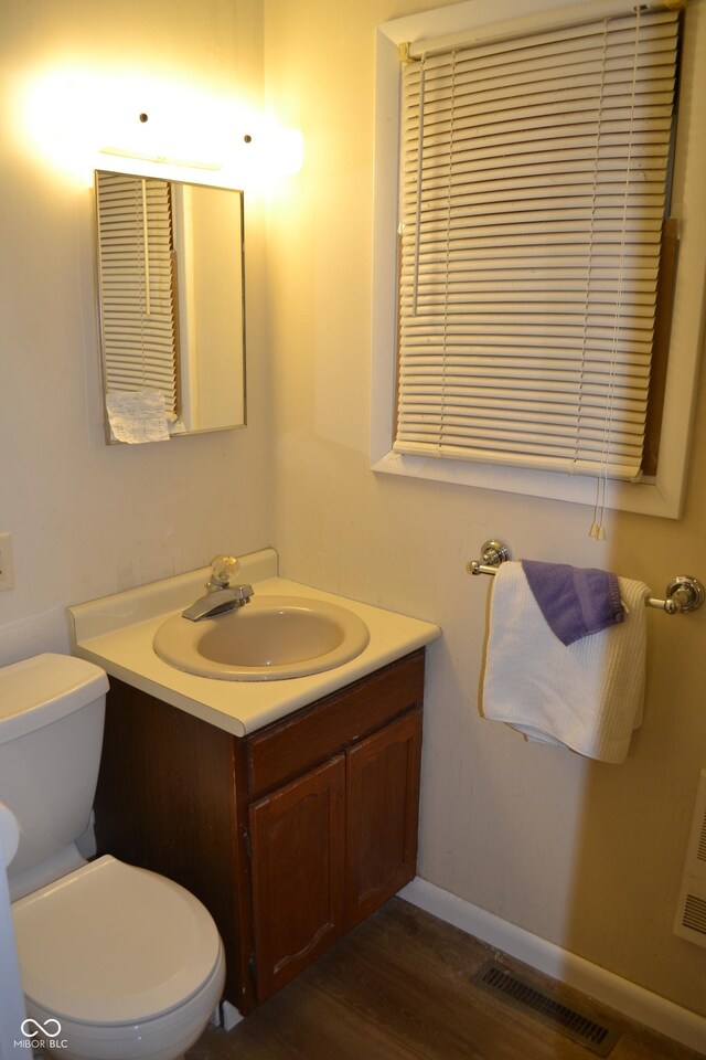 bathroom featuring vanity, toilet, wood finished floors, and baseboards