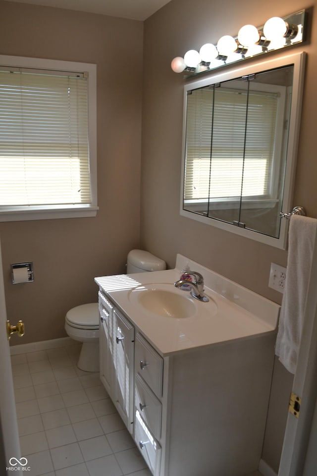 half bathroom featuring toilet, vanity, baseboards, and tile patterned floors
