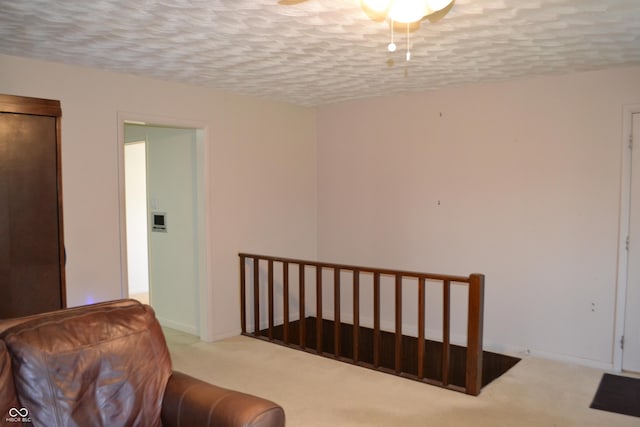sitting room featuring an upstairs landing, carpet floors, baseboards, and a textured ceiling