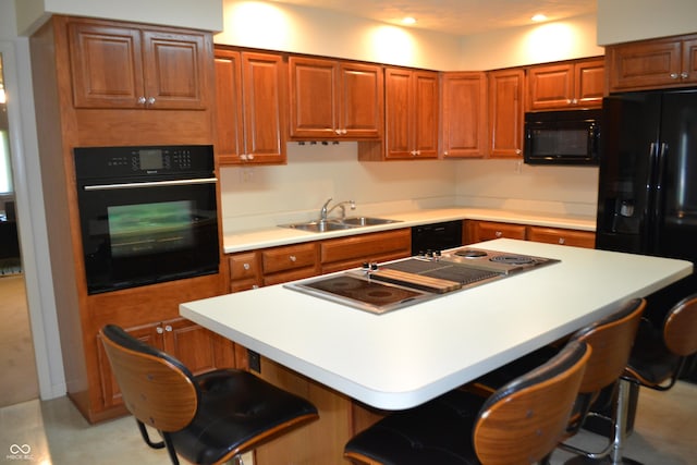 kitchen featuring black appliances, a sink, a kitchen breakfast bar, light countertops, and recessed lighting