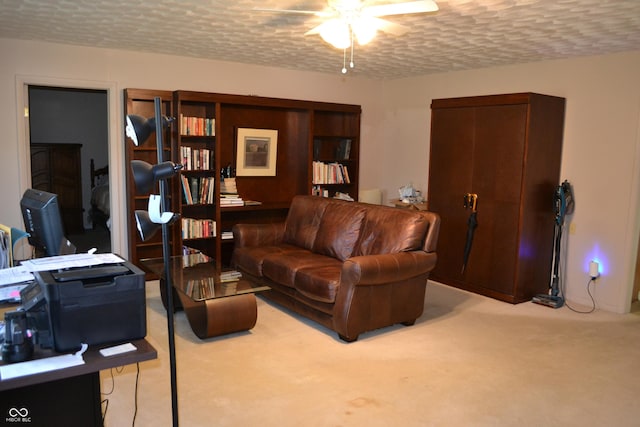 living area with a ceiling fan, carpet floors, and a textured ceiling