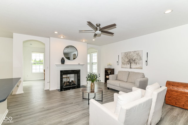 89 Kinnick Dr, Greenwood, IN 46143 - living room featuring arched walkways, a multi sided fireplace, a ceiling fan, light wood finished floors, and recessed lighting